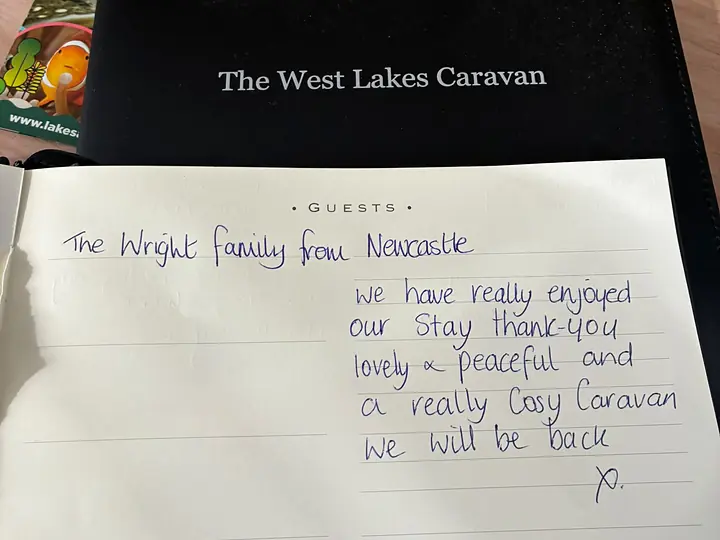 The guest book open on the table in The West Lakes Caravan with a handwritten entry from a family from Newcastle.