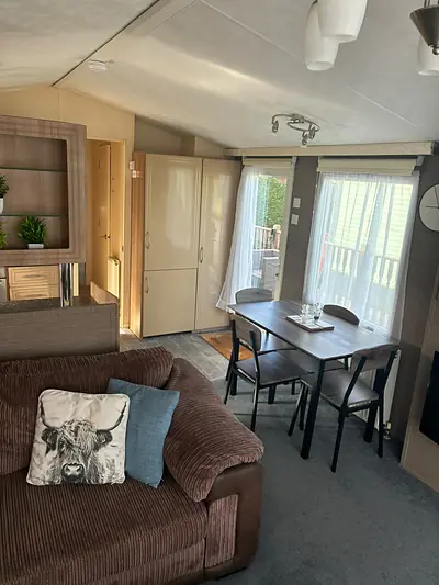 The corner sofa in The Lake District Caravan with a Highland cow cushion beside the dining table.