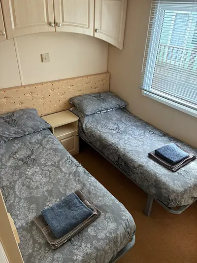 The twin bedroom in The West Lakes Caravan with a single bed made up and a towel folded at the foot.